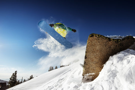 Snowboarder jumps from big rock. Sheregesh resort, Siberia, Russia