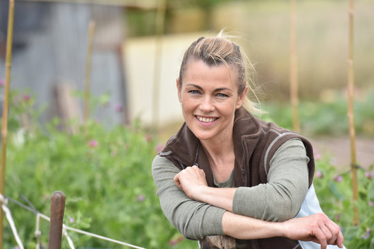 Cheerful woman farmer standing in vegetable garden