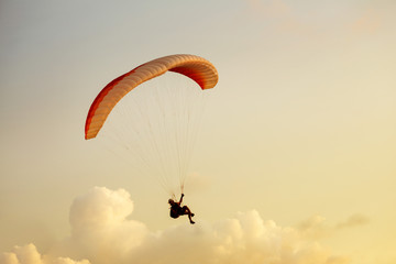 Paraglider flies on clouds backdrop