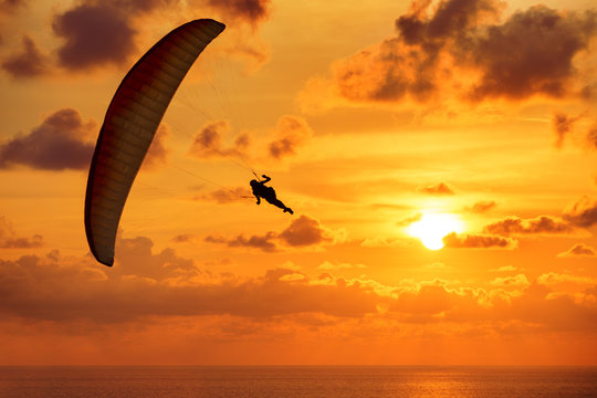 Paraglider flies on background of the sea and sunset