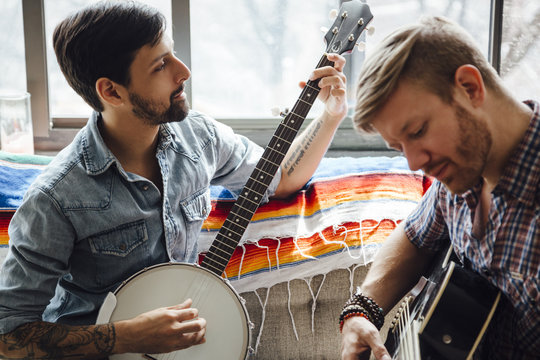 Male couple at home, play guitar and banjo