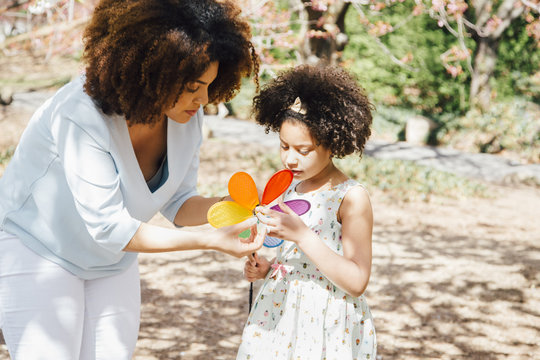 Mother helping daughter with colourful pinwheel toy