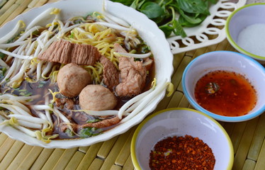 Chinese noodle with pork ball in brown soup and seasoning cup