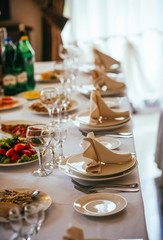 Flowers, wine glasses, napkins and salad on the table for the banquet.