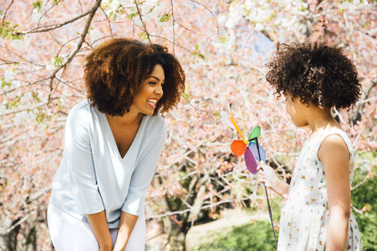 Mother smiling at daughter holding colourful pinwheel toy