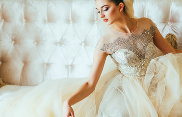 Fototapeta na wymiar photo of a beautiful brunette bride in a luxurious wedding dress lying on a sofa in elegant expensive interior