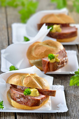 Street food bayerisch: Drei warme Leberkässemmeln mit Senf auf Papiertellern mit Serviette - Bavarian street food: Three rolls with meat loaf and mustard on paper plates  with white napkins