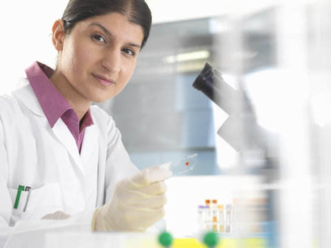 Portrait of female scientist testing blood samples using microscope - Powered by Adobe