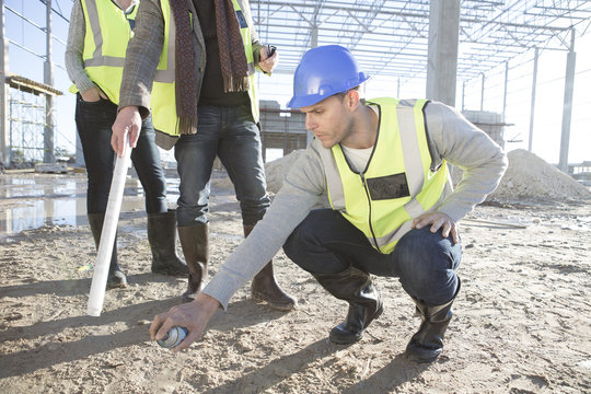 Architect marking floor area with spray can on construction site