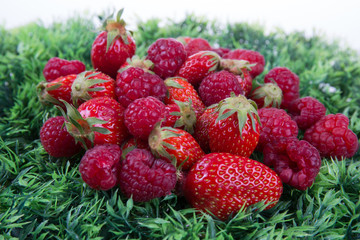 Ripe strawberry and raspberries isolated on a green background