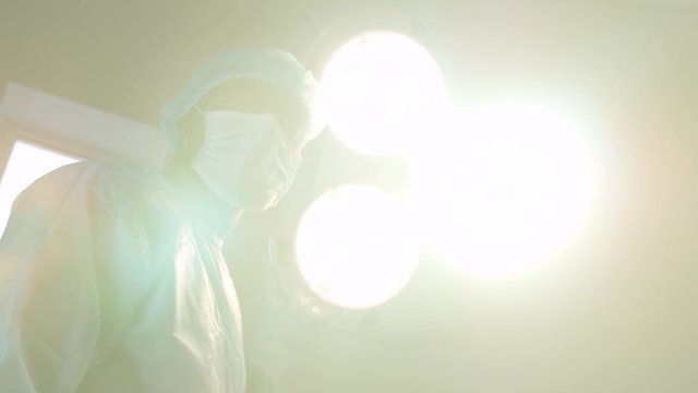 Surgeon in mask directs surgical light in camera