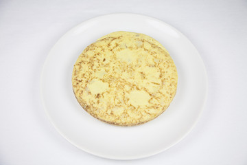 white dish with yellow spanish potato omelette on grey tablecloth
