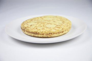 white dish with yellow spanish potato omelette on grey tablecloth
