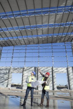 Surveyor and architect looking up at construction frame