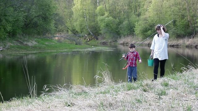 Cute pregnant woman with her six year old son go fishing on the banks of the river