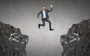 happy smiling businessman jumping between rocks