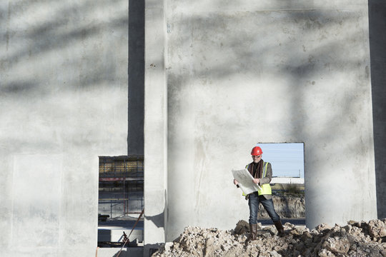 Surveyor reviewing blueprint on construction site