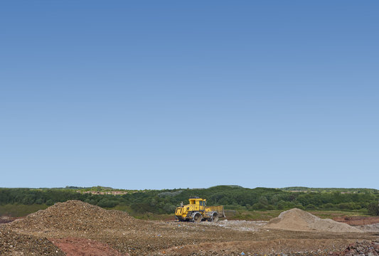 Digger burying waste on landfill site