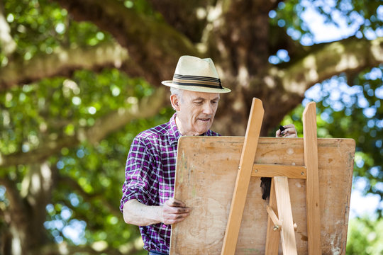 Senior man drawing in park, Hackney, London