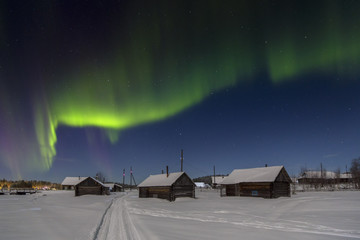 Village house in the lights of moon and Aurora borealis. Northern Karelia. Russia.