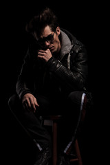 thoughtful young man in leather jacket sitting on chair