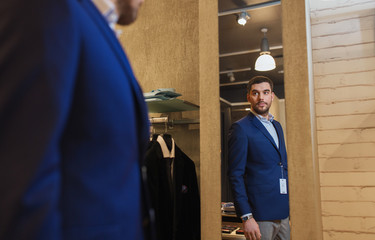 man trying jacket on at mirror in clothing store