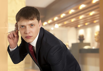 Businessman spying by listening through wall with glass