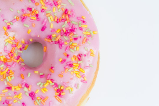 A large doughnut with hole and pink icing with sprinkles on an isolated white background.