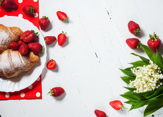 Delicious breakfast with fresh croissants and strawberries on white wooden background. Text place