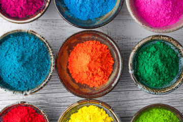 Obraz na płótnie Canvas Colorful Holi powder in cups closeup. Top view