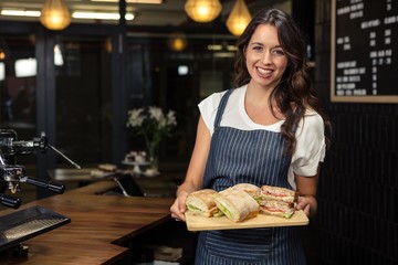 Smiling barista holding plate with sandwich