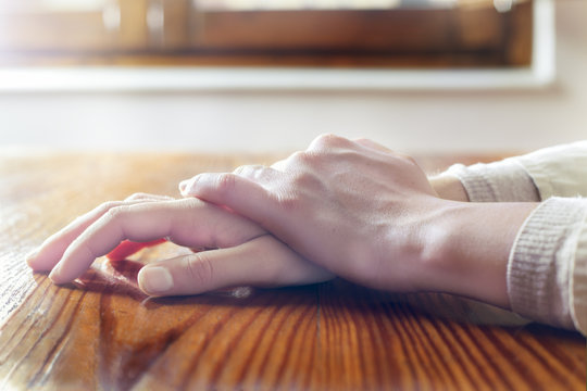 Close-up of woman hands in reflexive and relaxing position on wooden table