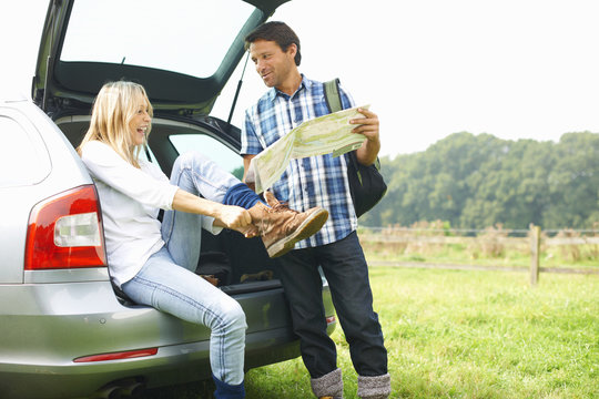 Couple at rear of car map reading preparing for walk