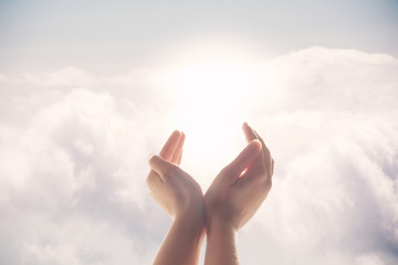 Hands raised up on a background of blue sky