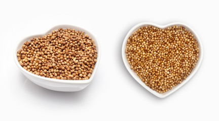 Coriander seeds  in a heart shaped bowl, isolated on white
