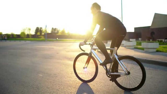 Man riding fixed gear bike on the road at sunset