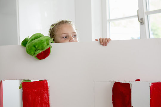 Girl peering over toy theatre with puppet