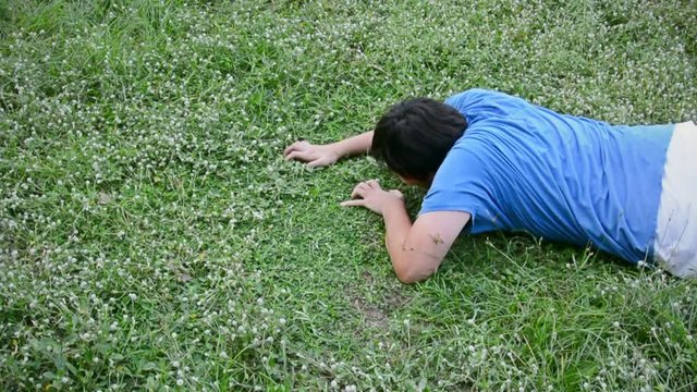 An Asian Thai guy struggling in a vast grass field but couldn't make it at last.