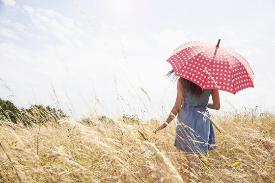Young woman in field with umbrella