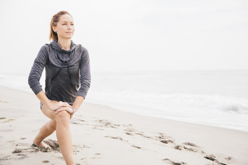 Young woman stretching on beach