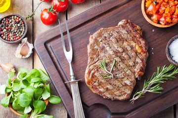 Beef steak with cherry tomato and rosemary on a dark cutting board Wooden background Top view