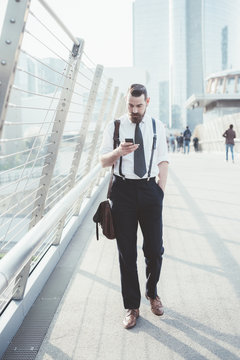 Businessman reading smartphone text update whilst walking on footbridge