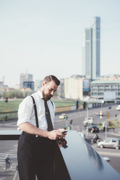 Businessman reading smartphone text update on office balcony