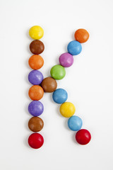La lettera K formata da coloratissimi confetti di cioccolato.