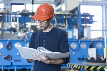 Factory engineer reading machinery instruction manual