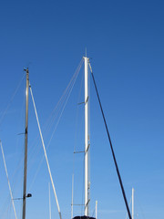 Obraz premium Sailboat masts in the marina against a blue summer sky