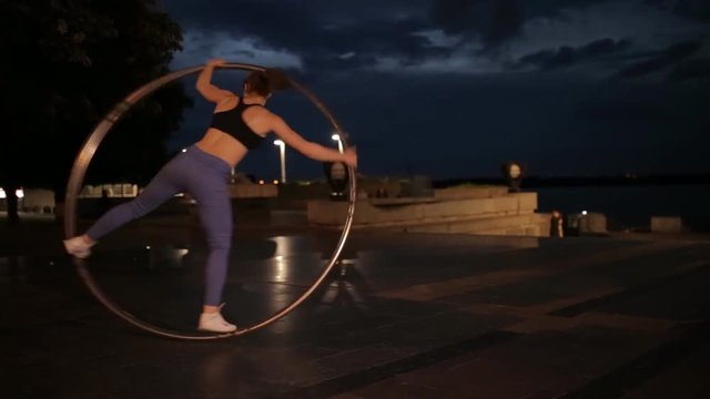 Woman on cyr wheel in city lights