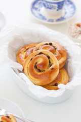 Fresh baked vanilla sweet sugar buns with chocolate drops in a bowl on a kitchen background