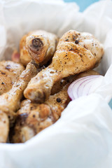 Roasted chicken legs with red onion, italian herbs, olive oil, pepper and salt in a bowl, closeup, selective focus