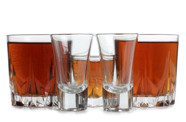 Glass jars with whiskey and ice on white background